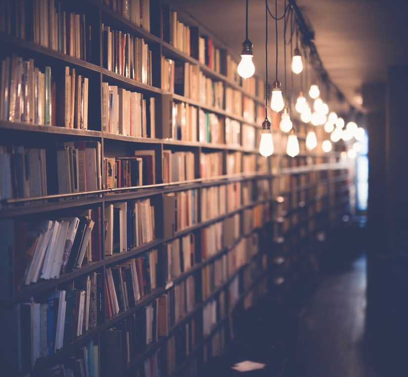 Gang einer Bibliothek, die mit hängenden Glühbirnen beleuchtet ist.