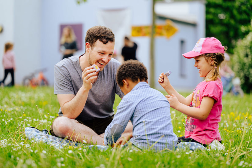 Erzieher sitzt mit Kindern im Gras