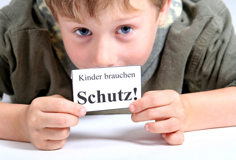 Kind mit Schild "Kinder brauchen Schutz!"