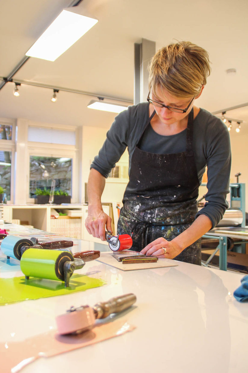 Christina Sauer bestreicht eine Druckplatte mit Farbe.