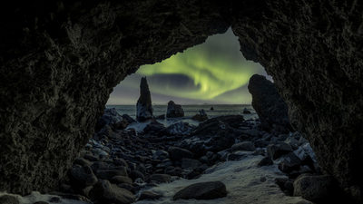 Durch Felsen eröffnet sich der Blick auf polarlichter über dem Meer