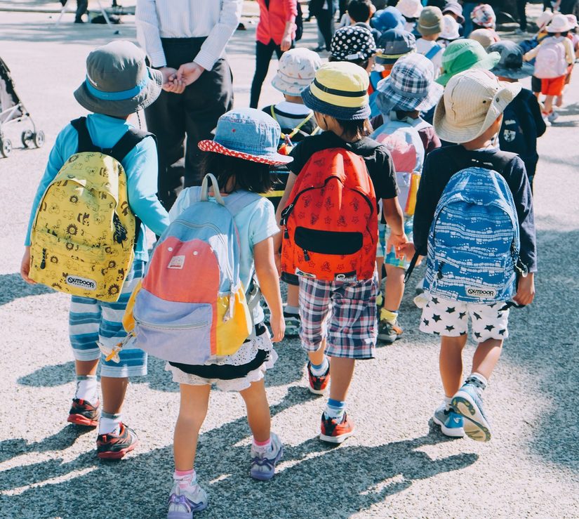 Gruppe von kleinen Kindern mit Rucksäcken und Hüten