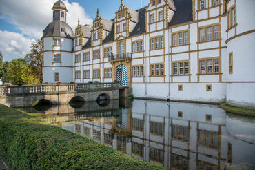 Foto der Rückseite der Schlossfassade mit Brücke und Wassergraben bei sonnigem Wetter.