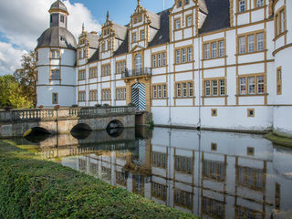 Foto der Rückseite der Schlossfassade mit Brücke und Wassergraben bei sonnigem Wetter.