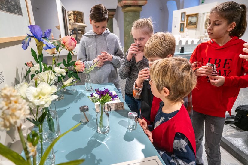 Fünf weiße inder, die um einen Display mit verschiedenen Blumen im Museum stehen.