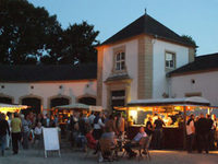 Mehrere Menschen sitzen in der Abenddämmerung zusammen und trinken Wein